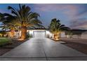 House exterior at dusk featuring palm trees, a driveway, and landscape lighting at 274 Doobie Ave, Las Vegas, NV 89183