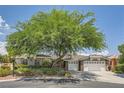 Single-story home with gray siding, mature tree, and attached two-car garage at 7456 Ute Meadows Cir, Las Vegas, NV 89129