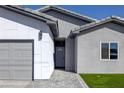 Modern home featuring a gray-tiled driveway leading to a stylish white front door and attached garage at 1308 E Nelson Ave, North Las Vegas, NV 89030