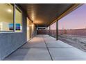 Covered back patio with gray concrete and a view of the block wall backyard at sunset at 3540 Valley Lily St, North Las Vegas, NV 89032