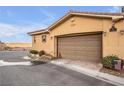 Two-car garage with a brown door and landscaping at 4 Via Centrale # 1, Henderson, NV 89011