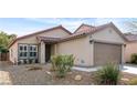 Tan house with red tile roof, landscaping, and a two-car garage at 8016 Roundup Ridge St, Las Vegas, NV 89131