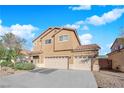 Two-story house with beige exterior, three-car garage, and landscaping at 2314 Rock Slide Cir, Las Vegas, NV 89115