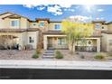 Tan two-story townhome with a paved walkway and landscaping at 675 Omaggio Pl, Henderson, NV 89011