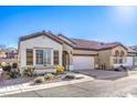 Attractive tan and white house with brown roof, landscaping, and attached garage at 2408 Sky Watcher St, Henderson, NV 89044