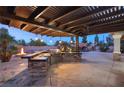 Outdoor kitchen with built-in grill, pergola, and stone countertops at 6004 Chessington Ave, Las Vegas, NV 89131