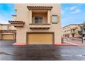 Tan colored garage with a balcony above it at 5925 Palmilla St # 12, North Las Vegas, NV 89031