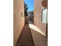 Narrow side yard with rock groundcover and walkway between the building and a gated entrance at 3025 Sunrise Bay Ave, North Las Vegas, NV 89031