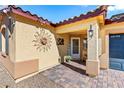 Front entry with a sun-shaped metal art piece and brick pavers at 2225 Chandler Ranch Pl, Laughlin, NV 89029