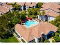 Aerial view showcases a community pool with palm trees, red umbrellas, and lush landscaping at 45 Maleena Mesa St # 223, Henderson, NV 89074