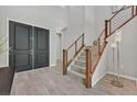 Modern entryway with dark gray double doors and a wooden staircase at 12031 Attiva Ave, Las Vegas, NV 89138