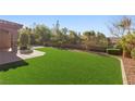 Expansive artificial turf backyard featuring mature landscaping, a stone patio, and perimeter fencing at 2717 Mona Lisa St, Henderson, NV 89044