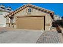 Tan house with a two-car garage and brick paver driveway at 6560 Bush Clover Ln, Las Vegas, NV 89156