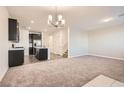 Open-concept living room featuring plush carpeting, modern light fixtures, and seamless flow into the kitchen at 762 Star Estates Ave, North Las Vegas, NV 89086
