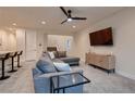 Open living room with sectional sofa, TV, and ceiling fan at 9181 Theodore Ct, Las Vegas, NV 89178