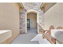 Inviting front entrance with a stone archway, decorative bench, and a view of the modern door, creating a welcoming ambiance at 10330 Glacier Mist Ave, Las Vegas, NV 89149