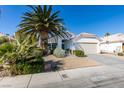 House exterior featuring a two-car garage and mature palm tree at 4421 Rodman Dr, Las Vegas, NV 89130