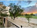 Landscaped backyard overlooking a golf course with sunset view at 5381 Waving Sage Dr, Las Vegas, NV 89149