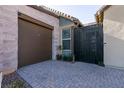 Brown garage door and modern black metal gate with brick paved walkway at 8435 Great Outdoors St, Las Vegas, NV 89166