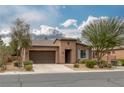 Single-story home with a tile roof, brown stucco, desert landscaping, and a two-car garage at 5625 Galivan Vista St, North Las Vegas, NV 89081