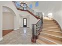 Grand foyer with a curved staircase, wrought iron railings, and a decorative tile inlay at 5790 Aspen Falls Cir, Las Vegas, NV 89149