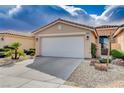 Beige home featuring a two-car garage, rock landscaping and mature trees at 5201 Progresso St, Las Vegas, NV 89135