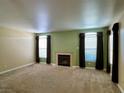 Bright living room with a fireplace, neutral walls, large windows, and brown carpet enhancing the cozy atmosphere at 8441 Blue Island Ave, Las Vegas, NV 89129