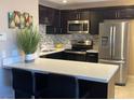 Modern kitchen features stainless steel appliances, dark cabinetry, and breakfast bar with white countertop at 1321 Cinder Rock Dr # 202, Las Vegas, NV 89128