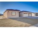 Tan home with two-car garage and gravel landscaping at 2140 Upland Ave, Pahrump, NV 89048