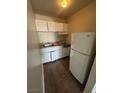 Small kitchen with white cabinets, stove, refrigerator, and tiled floor at 4600 University Center Dr # 95, Las Vegas, NV 89119