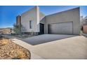 Modern home featuring a gray garage door and xeriscape landscaping, set on a hillside with a contemporary design at 623 Dragon Mountain Ct, Henderson, NV 89012