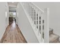 Bright hallway featuring durable wood floors and a staircase with carpeted treads and a white handrail at 43 Strada Loreto, Henderson, NV 89011