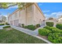 Tan two-story townhome with a gated entry and lush landscaping at 513 Rafkin Pl, Henderson, NV 89052