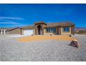 Attractive single-Gathering home featuring neutral tones, a two-car garage, and rock landscaping at 5821 Genoa Ave, Pahrump, NV 89060