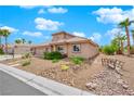 Single-story house with a tan exterior, a two-car garage, and landscaped front yard with a small bridge at 319 Hidden Highlands Dr, Las Vegas, NV 89110