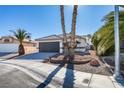 Single story home with a two car garage and desert landscaping at 7305 Backstretch Ave, Las Vegas, NV 89130