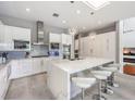 A modern white kitchen featuring a large marble island, stainless steel appliances, and stylish pendant lighting at 5 Clear Crossing Trl, Henderson, NV 89052