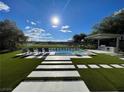 Backyard pool area with lounge chairs, an outdoor kitchen, green grass, and a beautiful golf course view at 5 Clear Crossing Trl, Henderson, NV 89052