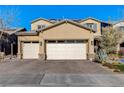 Two-story house with a beige facade, two-car garage, and landscaped yard at 1610 Dire Wolf Avenue, North Las Vegas, NV 89084