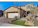 Two-story house with beige exterior, two-car garage, and nicely landscaped front yard at 1610 Dire Wolf Avenue, North Las Vegas, NV 89084