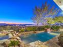 Stunning backyard pool area with rock features, waterfall, and scenic views of the surrounding landscape at 3 Pine Hollow Dr, Henderson, NV 89052