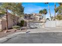 Two-story house with a tan exterior, two-car garage, and landscaped front yard at 8753 Arawana Pl, Henderson, NV 89074