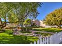 A charming home with a lush front lawn, picturesque landscaping, a white picket fence, and inviting curb appeal at 5110 N Valadez St, Las Vegas, NV 89149