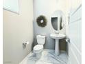 Small bathroom with pedestal sink, toilet, and marble floor at 12815 Alcores St, Las Vegas, NV 89141