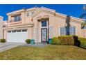 Two-story house with beige exterior, white garage door, and landscaped lawn at 8986 Lillyhammer Ct, Las Vegas, NV 89147