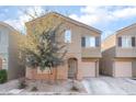 Beige two-story house with attached garage and a tree in front at 4129 Chamisa Cove St, Las Vegas, NV 89115