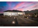 White stucco house with a three-car garage and desert landscaping at 4351 W Bell Vista Ave, Pahrump, NV 89060