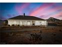 Back of house with covered patio and desert landscape at 4351 W Bell Vista Ave, Pahrump, NV 89060