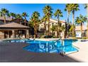 Community pool with surrounding lounge chairs and palm trees at 8250 N Grand Canyon Dr # 2073, Las Vegas, NV 89166