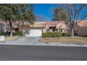 Tan two-story home with a red tile roof, attached garage, and landscaped front yard at 8608 Millsboro Dr, Las Vegas, NV 89134